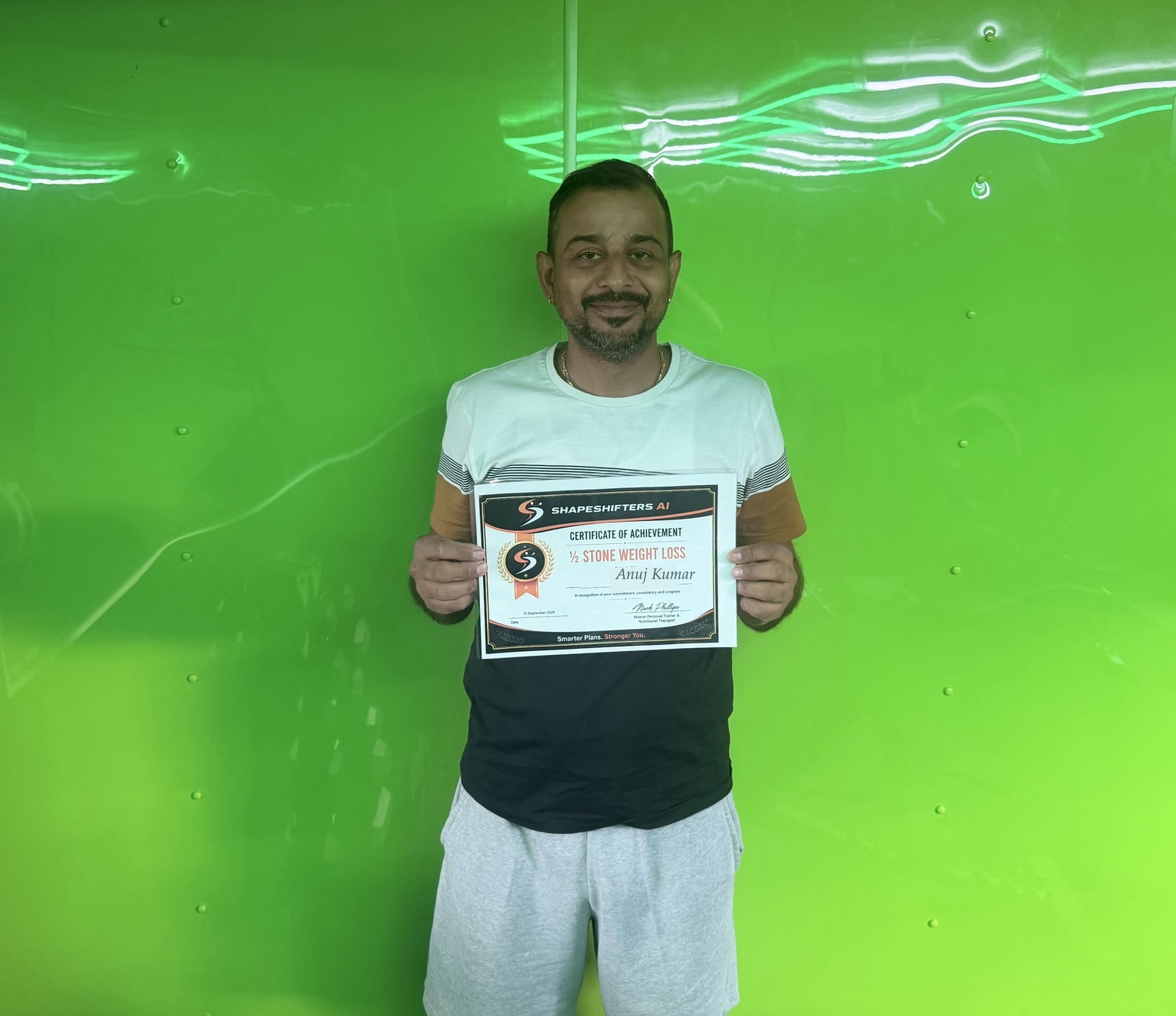 Anuj Kumar holding his ShapeShifters half-stone weight-loss achievement certificate