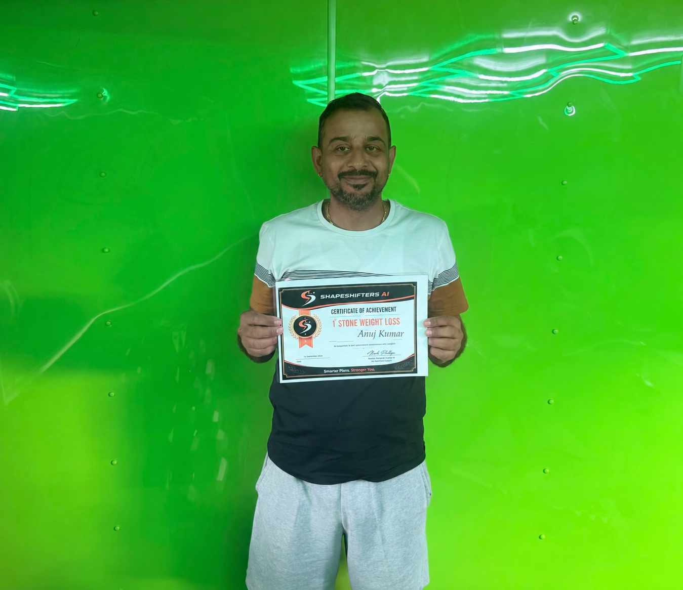 Anuj Kumar holding his ShapeShifters one-stone weight-loss achievement certificate